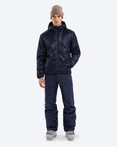 The Mountain Studio M-9 Pertex Insulated Midlayer in Sky Captain, on model front, styled with ski pants