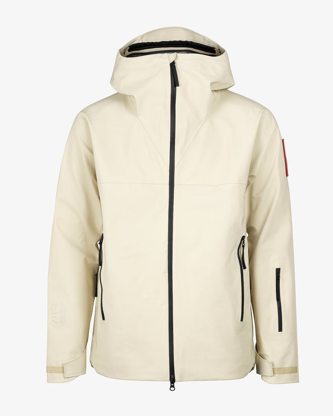 The Mountain Studio Z-4 shell jacket in beige, featuring a helmet-compatible hood, waterproof ALP-3 fabric, taped seams, and minimalist design with multiple zippered pockets.
